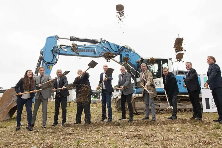 Beim ersten Spatenstich für das Aachener Zentrum für Holzbauforschung griffen Prof. Dr. Marcus Baumann, Rektor der FH Aachen (4.v.l.), Prof. Dr. Michael Wulf, Prorektor für Hochschulentwicklung (4.v.r.), Marco Herwartz, Präsident der Handwerkskammer Aachen (5.vl.), Bernd Goffart, Bürgermeister der Gemeinde Simmerath (3.v.l.) und die drei Holzbauprofessoren der FH Aachen, Prof. Dr. Thomas Uibel, Prof. Dr. Wilfried Moorkamp, Prof. Dr. Leif Arne Peterson (v.l.n.r., rechter Bildrand) zur Schaufel. Foto: FH Aachen l Nina E. Schreyer
