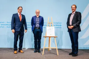 Architekt Christian Kirchberger (Mitte) erhielt den Preis vom Parlamentarischen Staatssekretär Florian Pronold (li.) und dem Leiter des Bundesumweltamts, Prof. Dr. Dirk Messner. Foto: Christoph Wehrer/BMU,